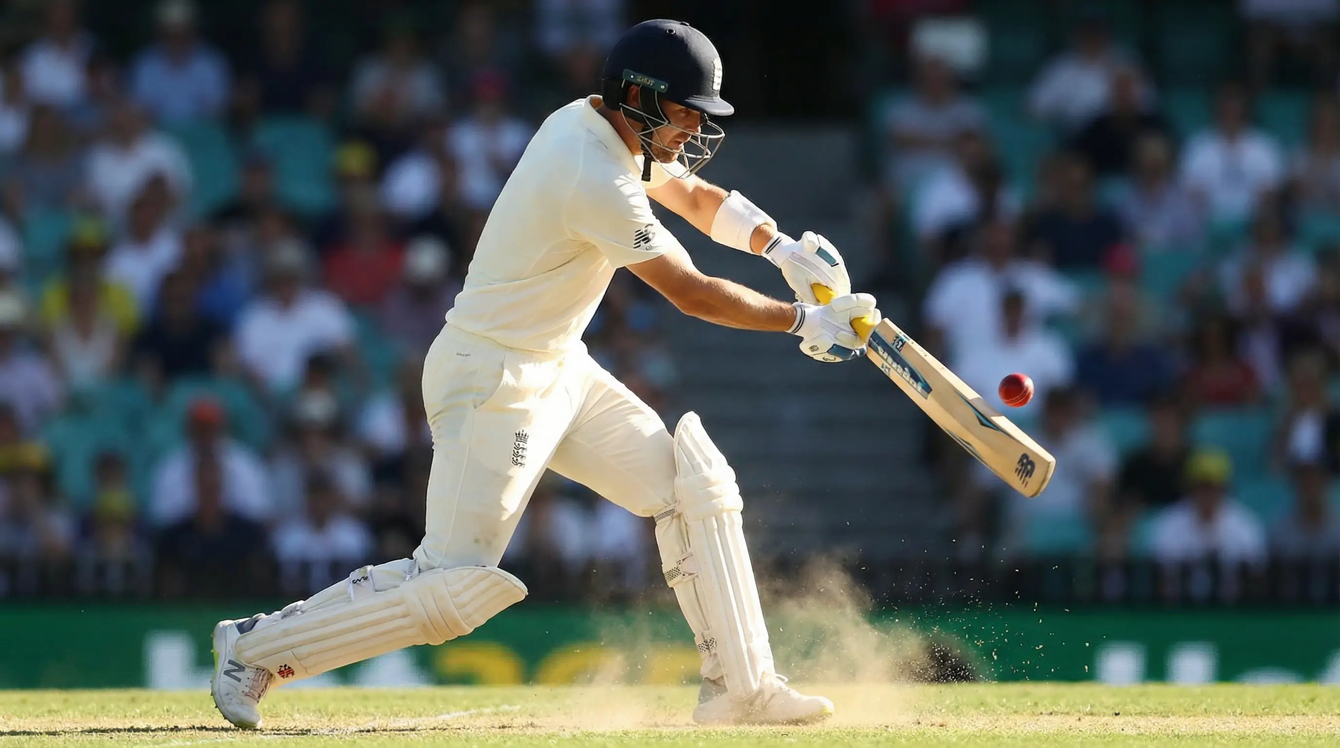 Cricket batsman playing a powerful shot with the ball flying toward the boundary on a sunny day